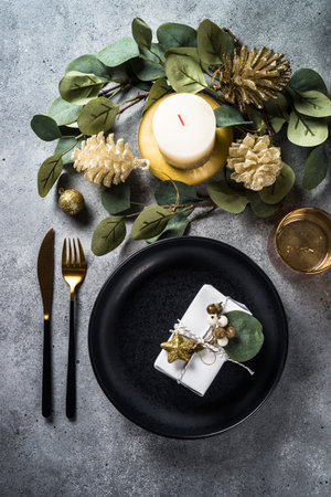 Christmas table setting with eucalyptus leaves and golden decorations.の写真素材