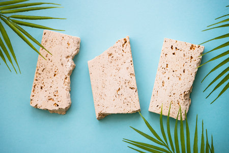 Travertine stone Podium with Palm leaves on blue background.