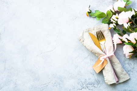 Table setting with white plate, cutlery and flowers.