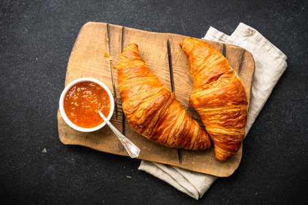 Croissant with jam on cutting board at stone table top view.の写真素材