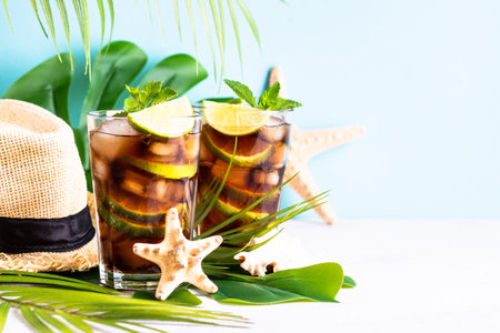 Cuba Libre alcoholic cocktail, iced drink with palm leaves and sea shells.の写真素材