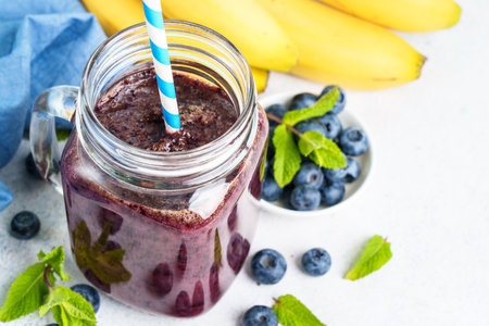 Blueberry banana smoothie in glass jar at blue background.の写真素材