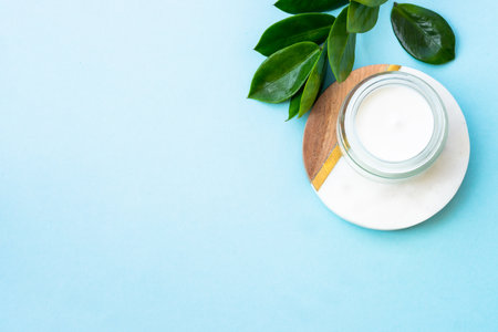 Natural cosmetic, cream jar with green leaves on blue.の写真素材