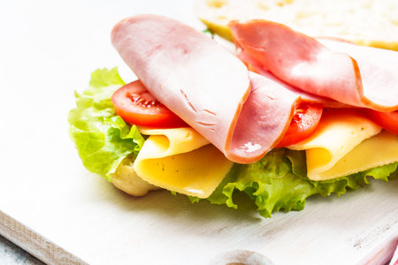 Ciabatta sandwich with lettuce, cheese, tomatoes and ham.の写真素材