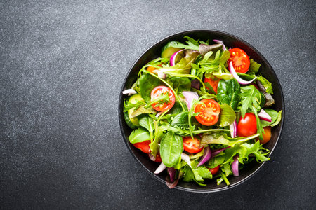 Salad in black bowl at dark background.の写真素材