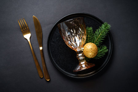 Christmas table with black plate, wine glass, napkin and cutlery.の写真素材