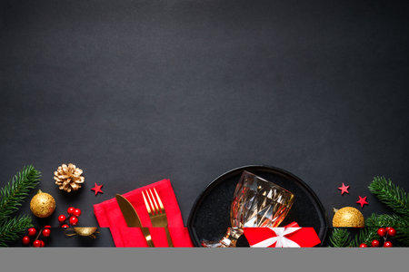 Christmas table setting with black plate, wine glass, cutlery and holidays decorations.の写真素材