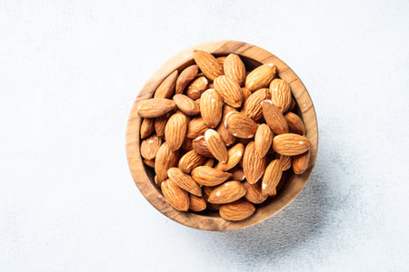 Almond nuts in wooden bowl at white background.の写真素材