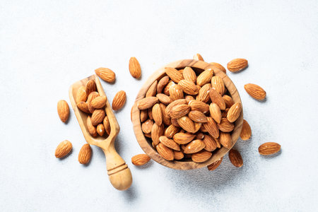 Almond nuts in wooden bowl at white background.の写真素材