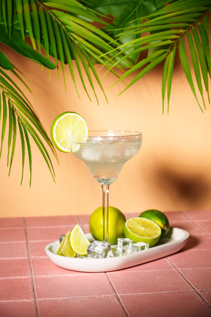 Margarita, traditional alcoholic cocktail with lime, silver tequila, ice cubes and salt. Pink tropical background with hard shadows.の写真素材