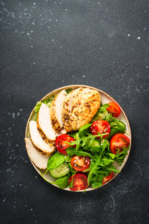 Green salad with grilled chicken meat at black table.の写真素材