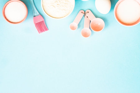 Ingredients for cooking baking on blue. Flour, sugar, eggs and utensils. Top view with space for text.の写真素材