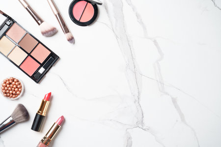Make up products at white marble background. Cosmetic palette, brushes and lipsticks. Top view with copy space.の写真素材