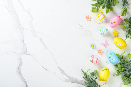 Easter composition with colored eggs and green plants on white background. Flat lay with copy space.の写真素材