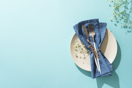 Easter table setting on blue. White plate, cutlery, and flowers.の写真素材