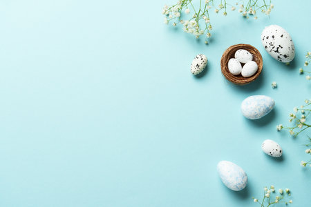 Easter flat lay background with eggs and flowers on blue.の写真素材