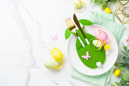 Easter table decor at white background. White plate, cutlery and funny decorations. Top view.の写真素材