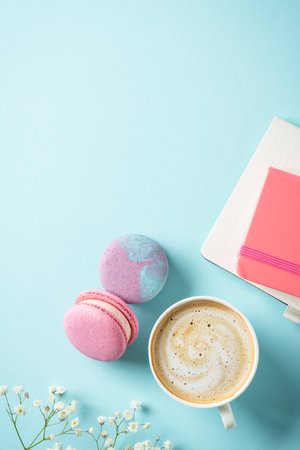 Flat lay background. Cup of coffee, macaroon and flower on blue background.の写真素材