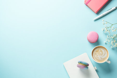 Cup of coffee, macaroon and flower on blue background. Top view with copy space.の写真素材
