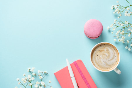Cup of coffee, macaroon and flower on blue background. Top view with copy space.の写真素材