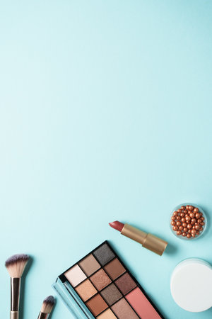 Make up products flat lay on blue. Cosmetic palette, brushes, lipsticks.の写真素材