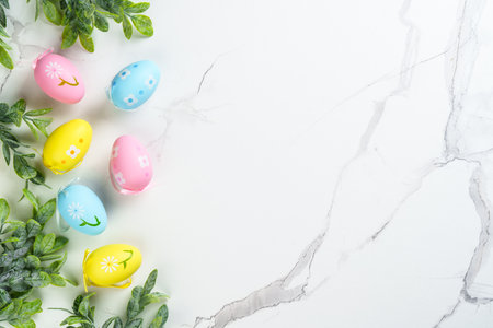 Easter composition with colored eggs and green plants on white background. Flat lay with copy space.の写真素材