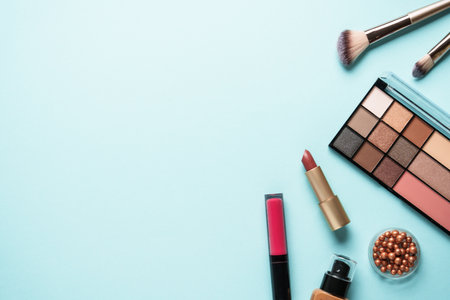 Beauty products on blue background. Cosmetic palette, brushes and lipsticks. Top view with copy space.の写真素材
