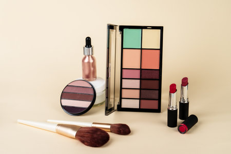 Makeup products. Eyeshadow palette, cream jar, lipsticks and brushes on colored background.の写真素材
