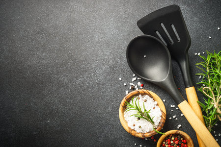Kitchen table with utensils, herbs and spices on black. Top view with space for design.の写真素材