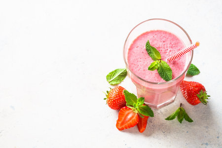 Strawberry smoothie or milkshake in glass at white table. Flat lay image with copy space.の写真素材
