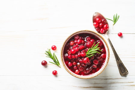 Cranberry sauce in a bowl at white wooden table. Top view with space for text.の写真素材