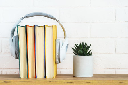 Audio books concept. Wireless Headphones and color books at table white background.の写真素材