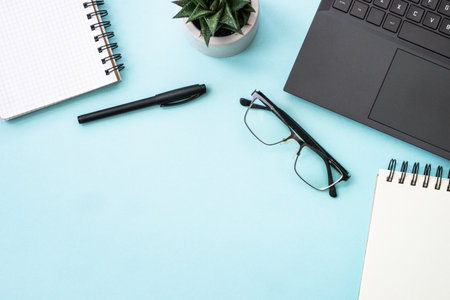 Office desk flat lay background with laptop, notepad, green plant and pen.の写真素材