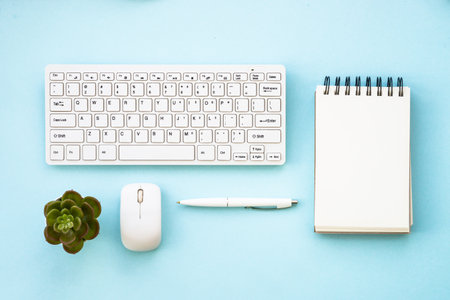 Office desk flat lay background with keyboard, notepad, green plant, mouse and pen.の写真素材
