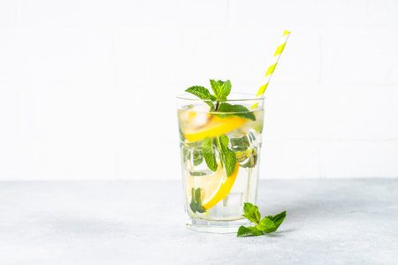 Lemonade in glass on white table. Cold summer drink with ice.の写真素材