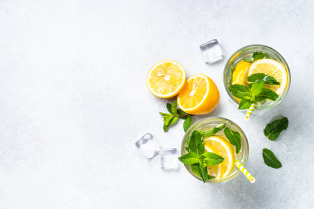 Lemonade in glass with fresh lemons and mint. Cold summer drink top view with copy space.の写真素材