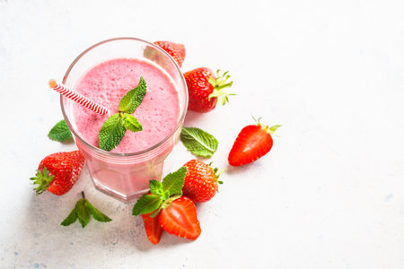 Strawberry smoothie or milkshake with fresh berries at white table.の写真素材