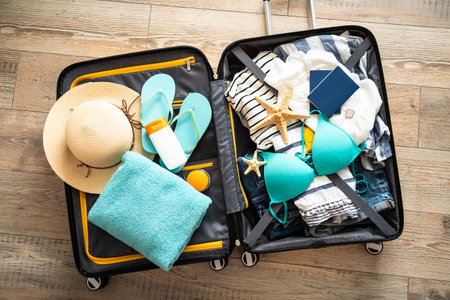 Open Suitcase with summer cloth, hat and passports. Travel concept. Flat lay image on wooden background.の写真素材
