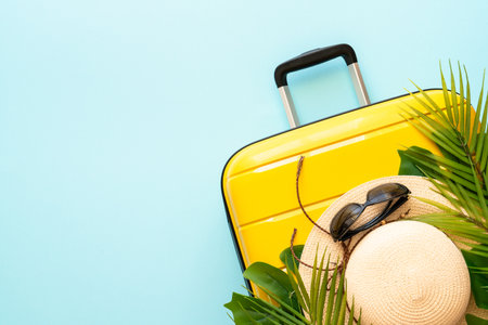 Summer holidays, traveling concept. Suitcase, hat and palm leaves on blue background. Flat lay with space for text.の写真素材