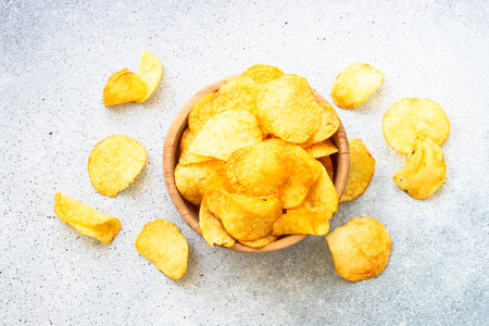 Potato chips in wooden bowl on white table. Top view.の写真素材