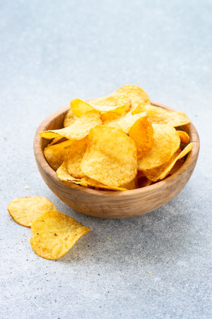 Potato chips in wooden bowl on white table. Top view with copy space.の写真素材