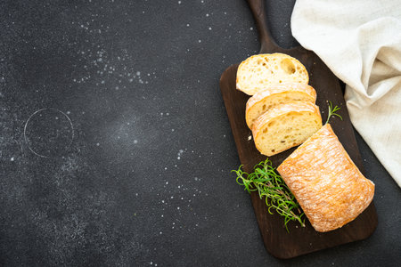Ciabatta bread on wooden board on black background. Top view with copy space.の写真素材