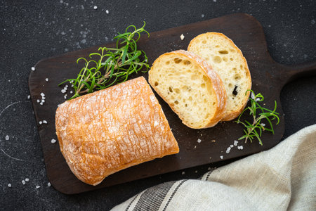 Ciabatta bread on wooden board on black background. Top view with copy space.