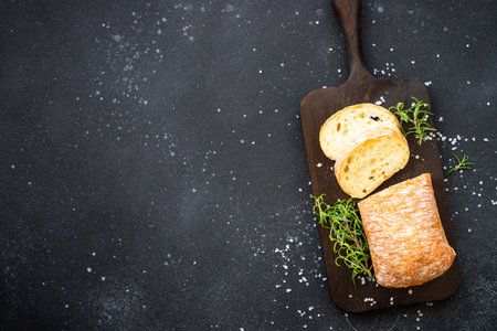 Ciabatta bread on wooden board on black background. Top view with copy space.の写真素材