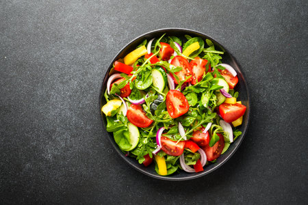 Fresh salad with leaves and vegetables. Top view on black.の写真素材
