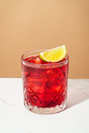 Strong alcohol cocktail. New Yorker with whiskey, grenadine, bitter, lime and ice oncolored background.の写真素材