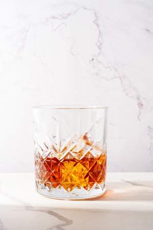 Whiskey with ice cube in the glass at white table.の写真素材