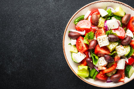 Greek salad in craft plate on black background. Top view. Vegan food, mediterranean diet.の写真素材