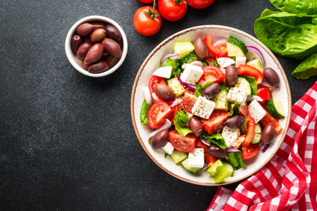 Greek salad in craft plate on black kitchen table. Top view. Vegan food.の写真素材
