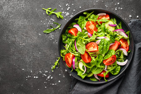 Fresh salad with leaves and vegetables. Top view with space for design on black background.の写真素材